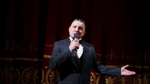 Man in Tuxedo Hosting Event on Stage