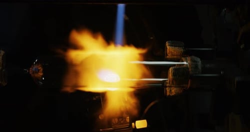 Slow motion macro of glass blower working with flame on a handmade art piece of glass from preciou