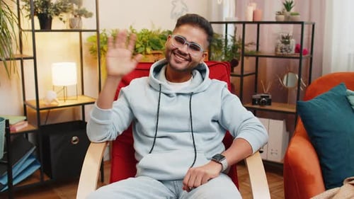 Young Man Waving and Smiling in Living Room