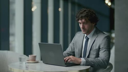 Businessman Working on Laptop and Drinking Coffee in Cafe