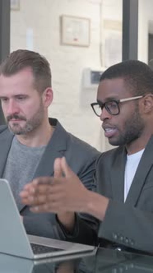 Men Talk and Point at Laptop in Office Setting