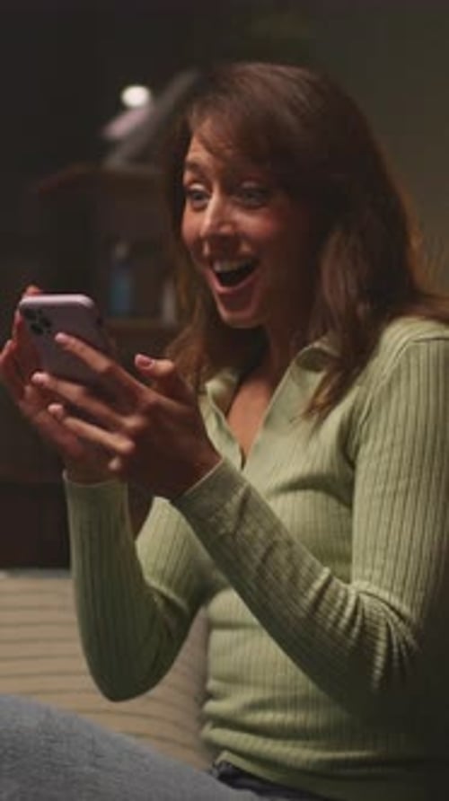 Joyful Woman Celebrating Woman Dressed in Green Sweater Expresses Joy While Celebrating Indoors with