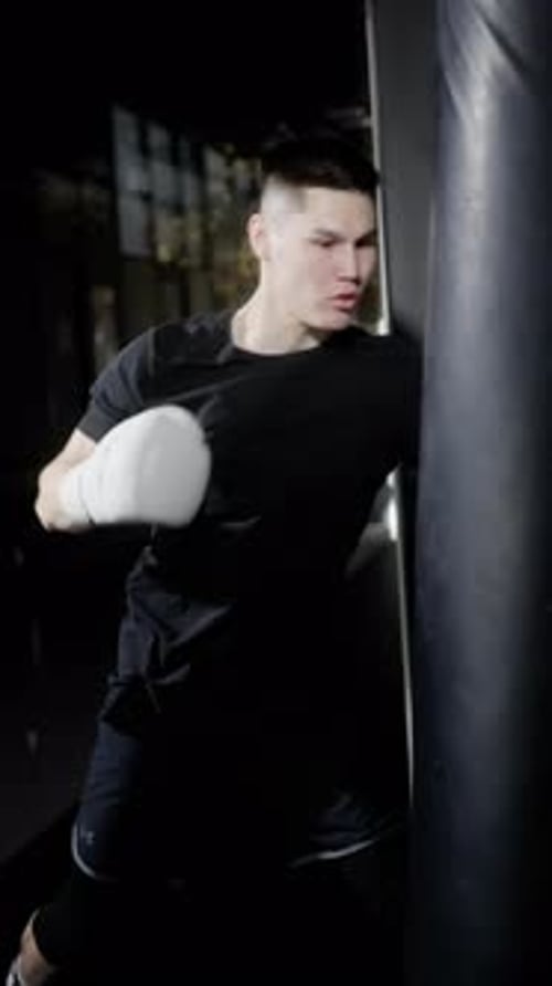 Focused Young Man Boxing With Punching Bag
