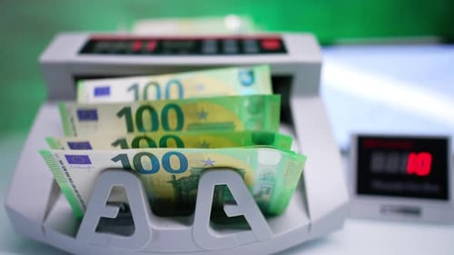 Money placed into automatic cash counting machine. Green hundred euro bills appear from device.
