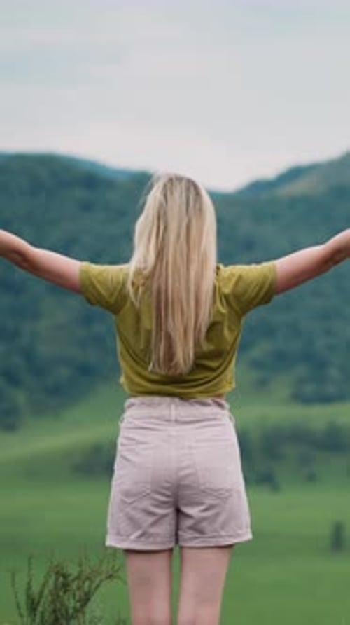 Graceful Woman Hiker with Raised Hands Enjoys Green Valley