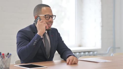 Businessman Talking on Mobile Phone at Office Desk
