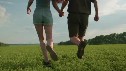 Back View Lovers Jogging Across Open Field Holding Hands