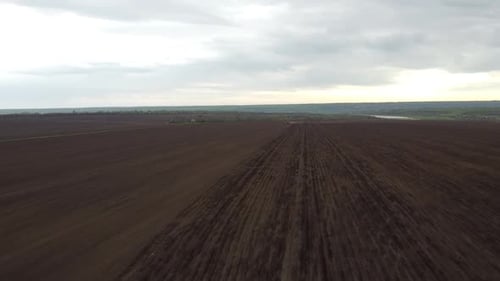 Blue tractor with yellow seeder working on the field in Ukraine OA