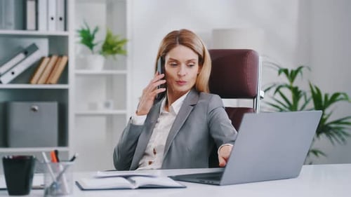 Talking by phone. Woman in business formal clothes is working in office