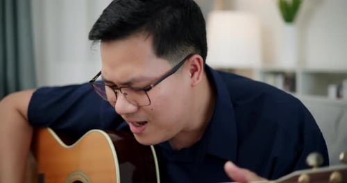 Man Playing Acoustic Guitar and Singing Indoors