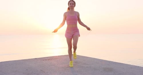 Fit woman jumping rope at the beach during summer vacation. Slow motion