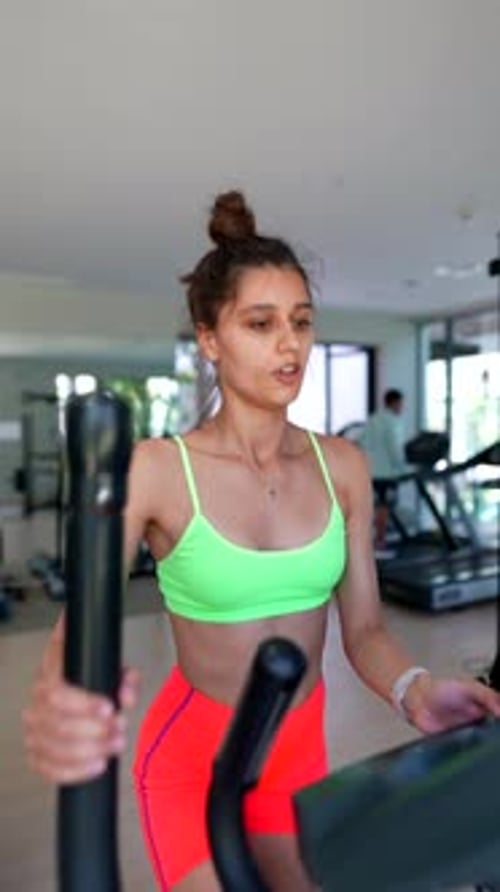 A Woman Energetically Works Out on an Elliptical Machine at the Gym Showing Dedication to Fitness