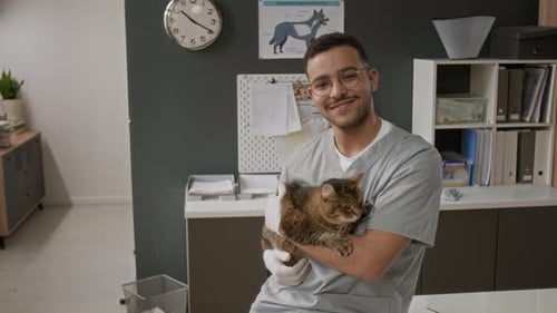 Portrait of Smiling Male Veterinarian Holding Cat in Clinic Office
