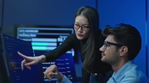 Two Developers Reviewing Code Together On Office Monitor