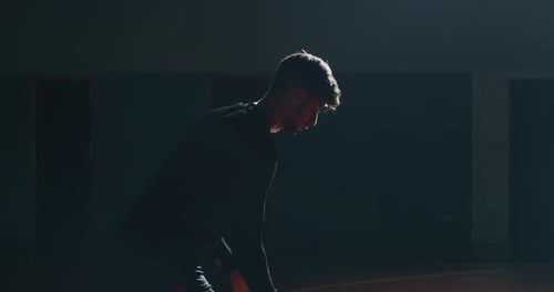 Cinematic slow motion shot of an young professional male player is making a slam dunk during a bas