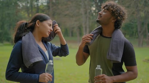 Tired Exhausted Indian Man and Woman Relaxing After Sports in Park Outdoor Arabian Fitness Couple in