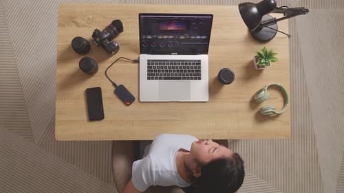 Vista superior de una mujer asiática que gradúa el color con dolor de espalda mientras usa una computadora portátil editando el Vídeo