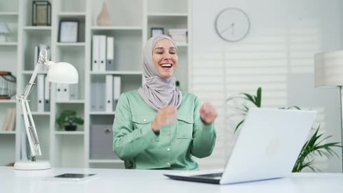 A satisfied glad young female muslim worker employee relaxes after finishing work on a laptop comput