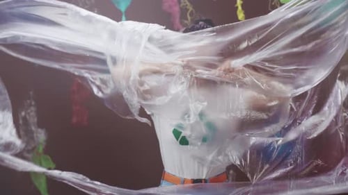 Un militant écologiste arrêté dans un filet en plastique, un individu immergé dans des déchets plastiques, dénonçant la pollution et