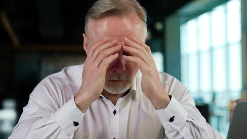 Stressed Man Holding Head at Office Desk
