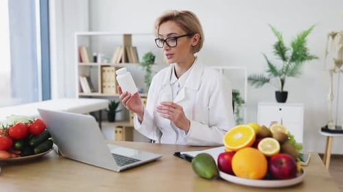 Woman with Vitamins and Fruits on Video Call