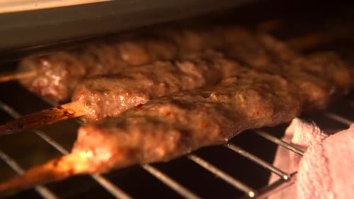 Cooking pork kebab in mini oven. Close-up of baking hot grill in the oven.