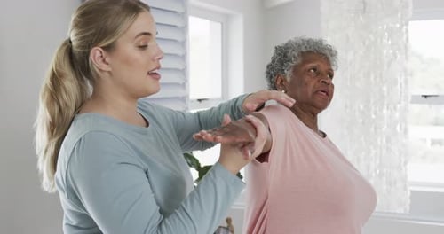 Woman Assists Senior with Arm and Shoulder Stretch
