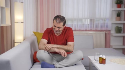 Man Rubbing Arm and Knee in Discomfort