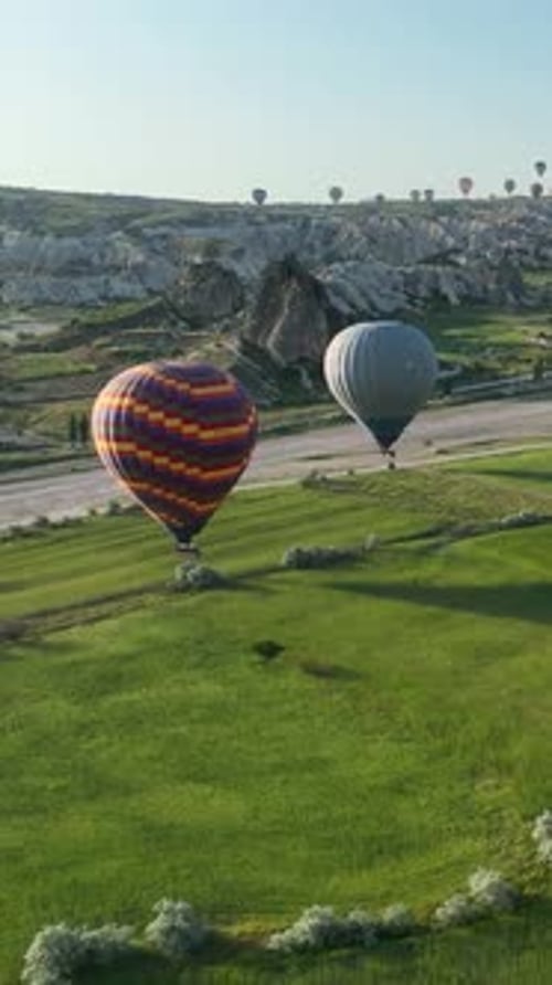 Vertical Video Hot Air Balloons Fly Over the Mountainous Landscape of Cappadocia Turkey