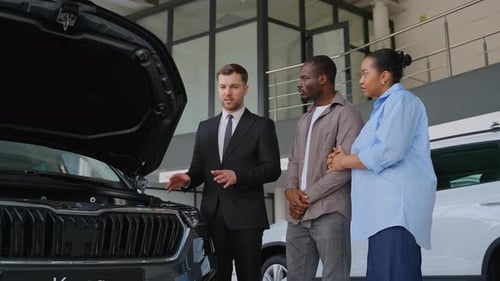 Salesman Explaining Car Features to Adult Couple