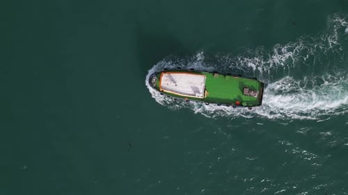 Luftaufnahme eines Schleppers, der über das offene Meer fährt und eine starke weiße Welle auf dunkelblauem Wasser hinterlässt