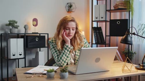 Bored Sleepy Businesswoman Worker Working on Laptop Computer Yawns Leaning on Hand at Office Desk