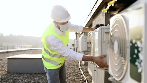 Man Inspecting Air Conditioning Unit on Roof