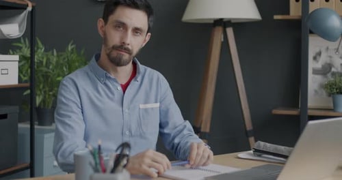 Man Sitting at Desk Looking at Camera