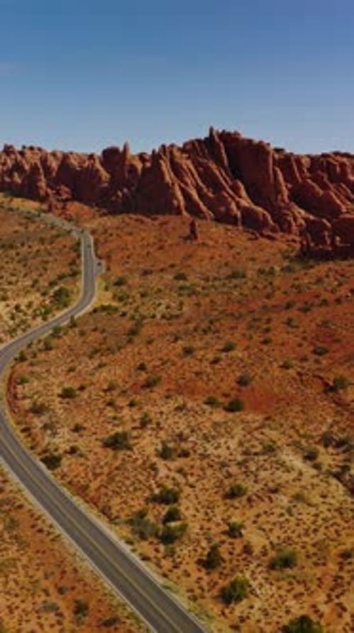 Dry desert with little greenery and road going through it. Beautiful canyons of Arches National park