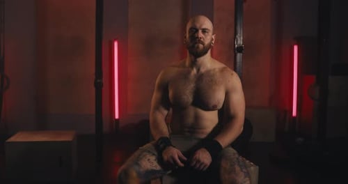 Portrait of a Serious Male Athlete with Muscles Without a Shirt Who is Posing in a Modern Gym with