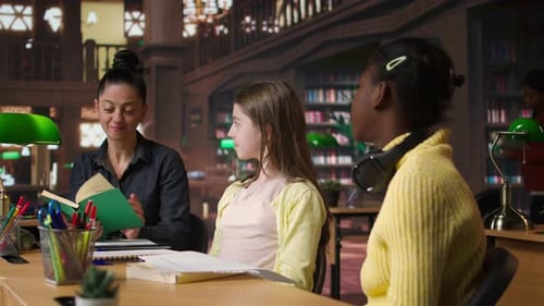 Woman Teaches Two Children At Library Table