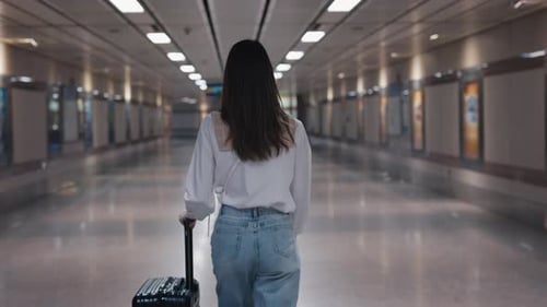 Female with Rolling Suitcase Walks Along Passenger Tunnel at Railroad Station