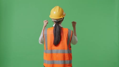 Back View Of A Female Engineer With Safety Helmet Raising Her Hands Celebrating In The Green Screen