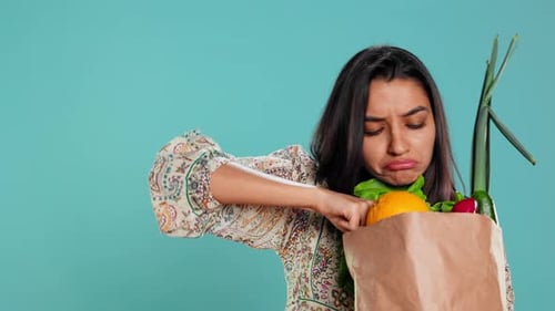 Mujer con una bolsa de papel ecológica en las manos mirando un pimiento