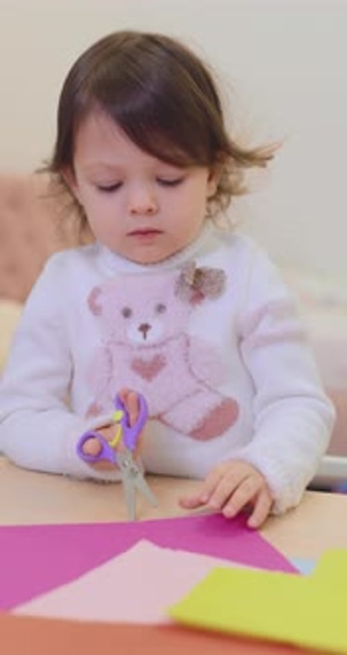 Little Girl Cutting Paper with Scissors Indoors