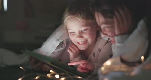 Girls Under Blanket Using Tablet at Home