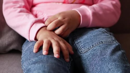 Child Sitting and Scratching Hand Close Up