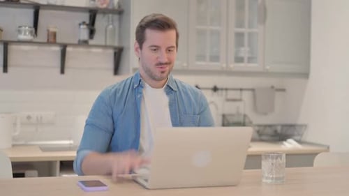 Man on Video Call Waving at Laptop in Home