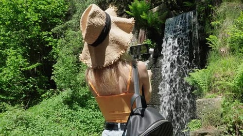 Woman Films Waterfall in Lush Green Park