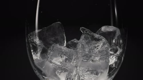 Water Pouring on Ice Cubes in Clear Glass
