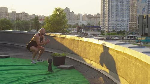 Muscular Man Doing Jump Squats on Rooftop