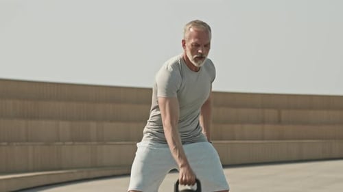 Senior Man Exercising with Kettlebell Outdoors