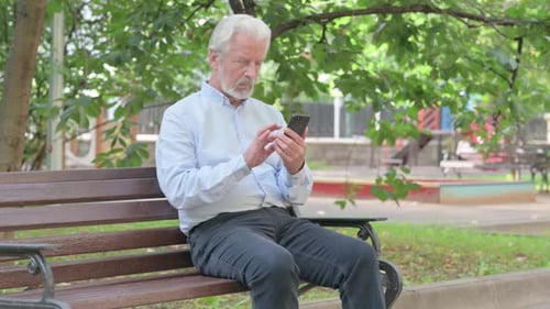Senior Man Using Smartphone on Park Bench