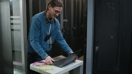 Network Engineer Coding on Laptop while Coordinating Data Center Operations